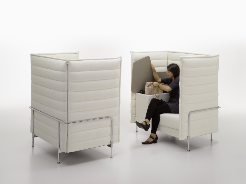 Frau verstaut Tasche im weißen Alcove Highback Sessel von Vitra, Büromöbel für konzentriertes Arbeiten.