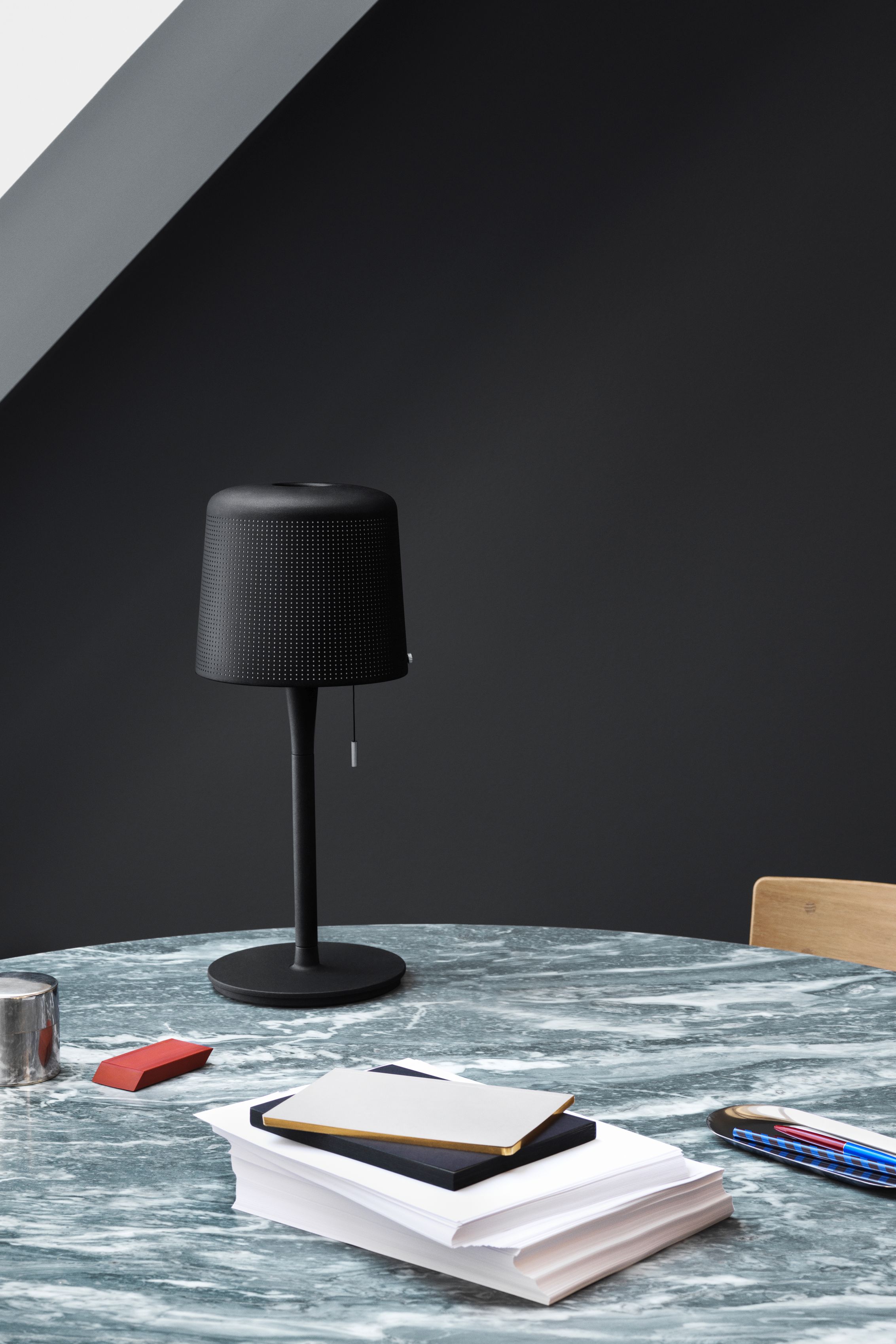 Schwarze Vipp Tischleuchte auf einem Marmortisch mit Büromaterialien, ideal als Nachttischlampe oder Schreibtischleuchte.