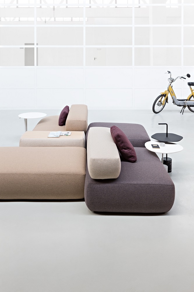 PLUS D215 Pouf: Modulares Sofa-System mit beigen und grauen Sitzelementen und lila Kissen.