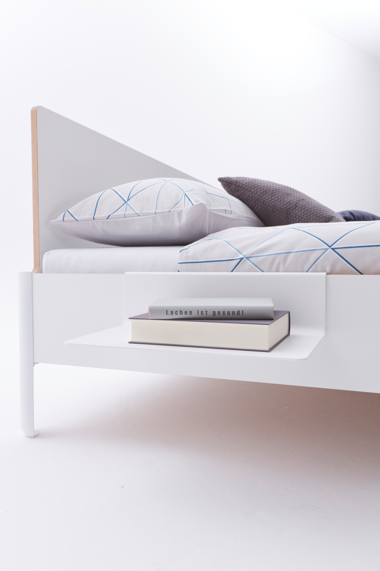 Detailaufnahme des weißen Nait Betts von Müller Möbelwerkstätten mit Kopfteil und Ablage.