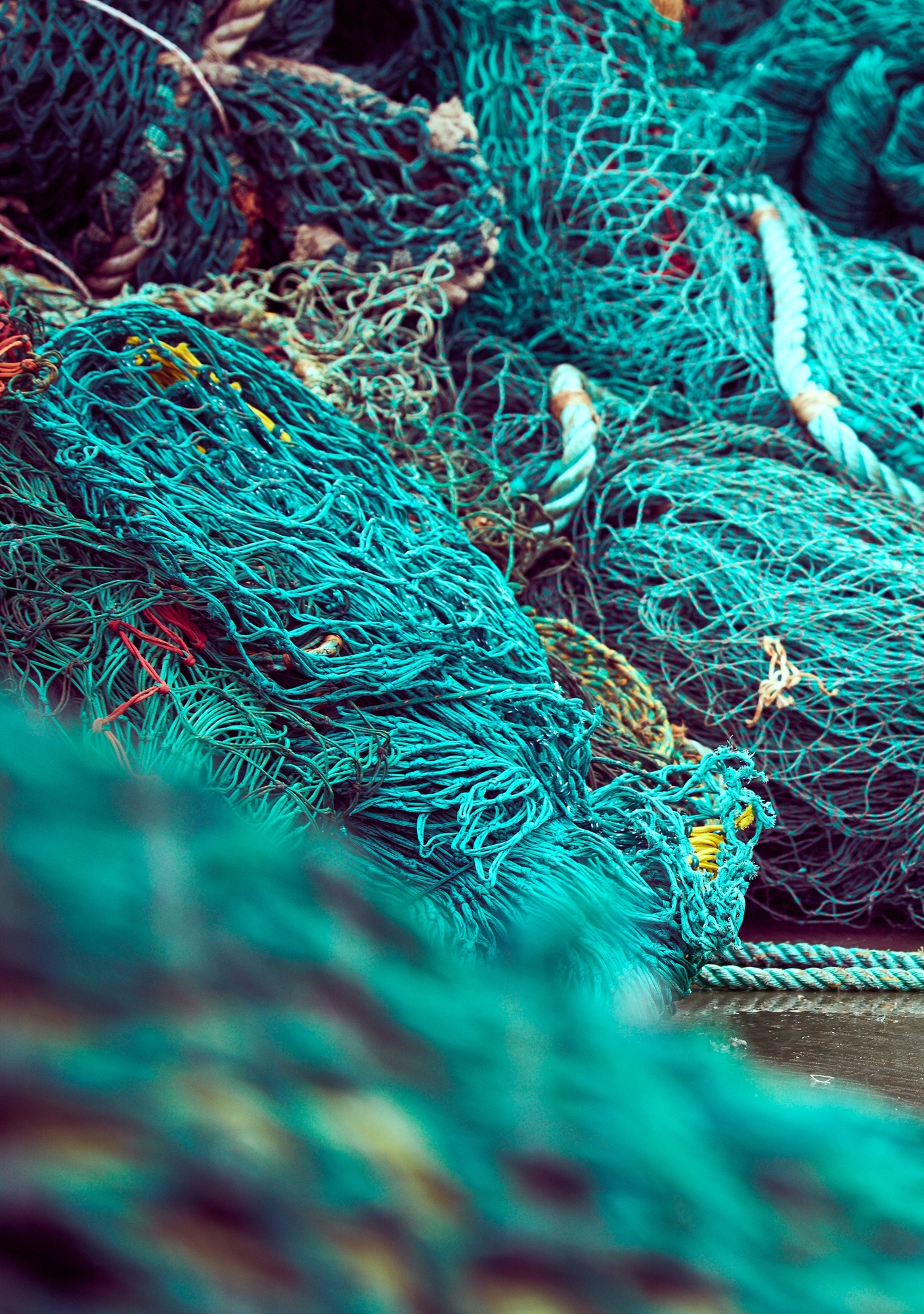 Nahaufnahme von Fischernetzen und Seilen in Türkis-, Blau- und Brauntönen.