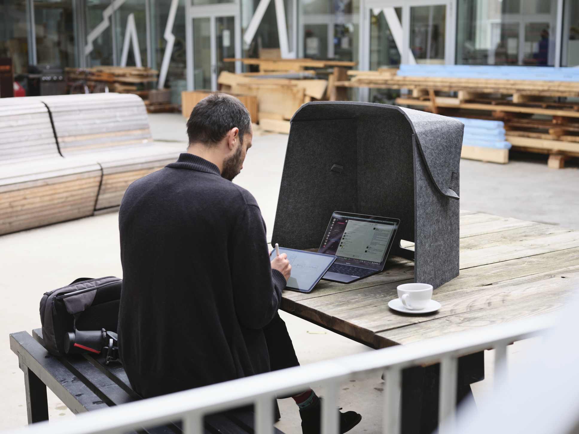 Mann arbeitet mit Laptop und Tablet im Fold-Up-Workspace von Wilkhahn im Freien.