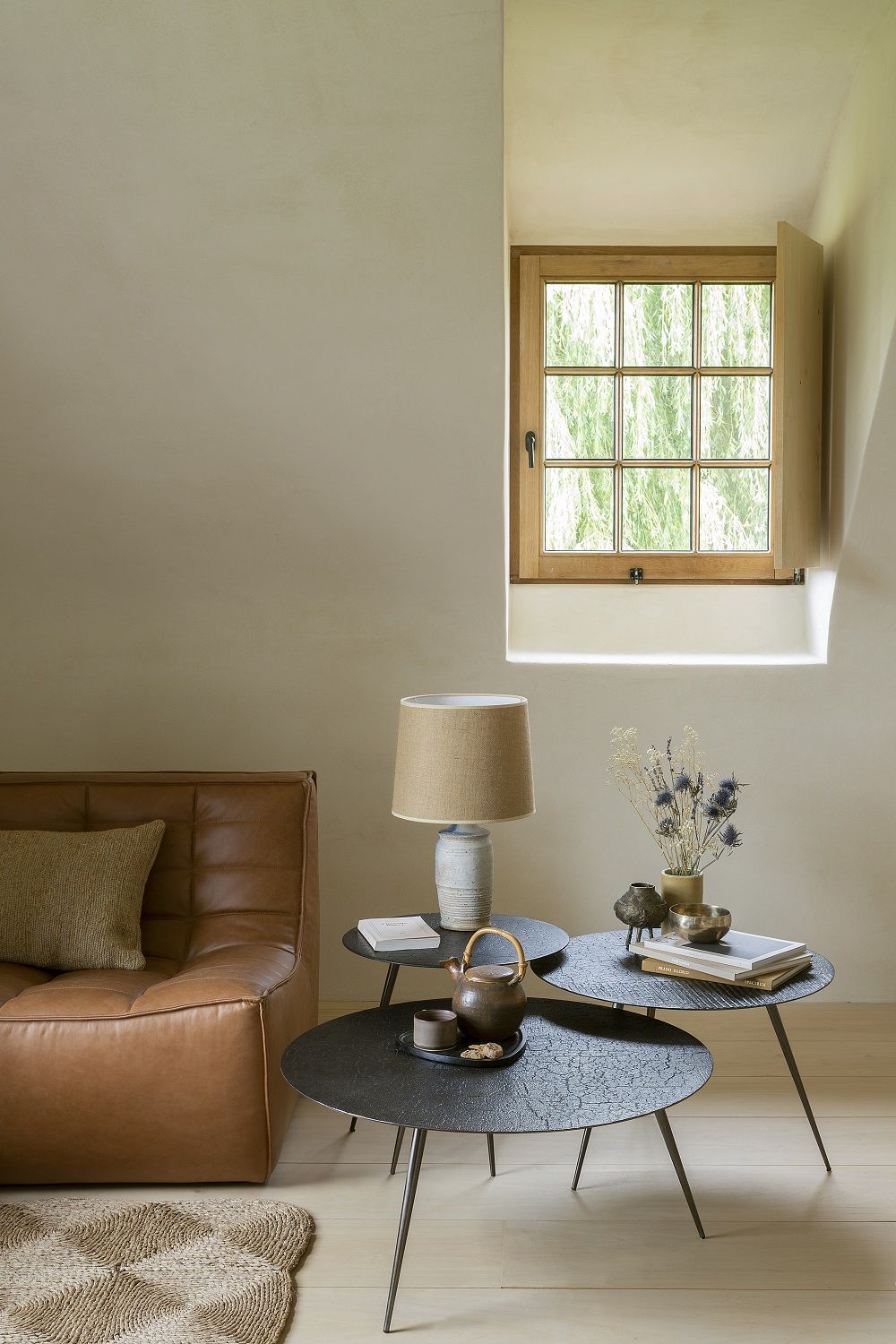 Luna Couchtisch von Ethnicraft, Durchmesser 50 cm, in einem stilvollen Wohnzimmer mit Teekanne und Dekoration.