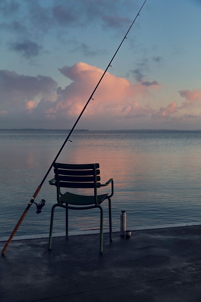 Houe ReClips Outdoor Stuhl am See mit Angel und Thermoskanne im Sonnenaufgang.