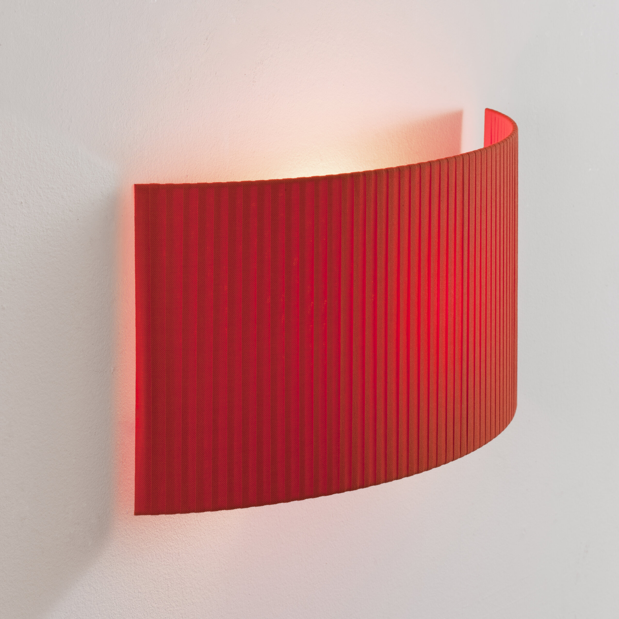 Rote Comodín Wandleuchte von Santa & Cole mit geripptem Stoffschirm an weißer Wand.
