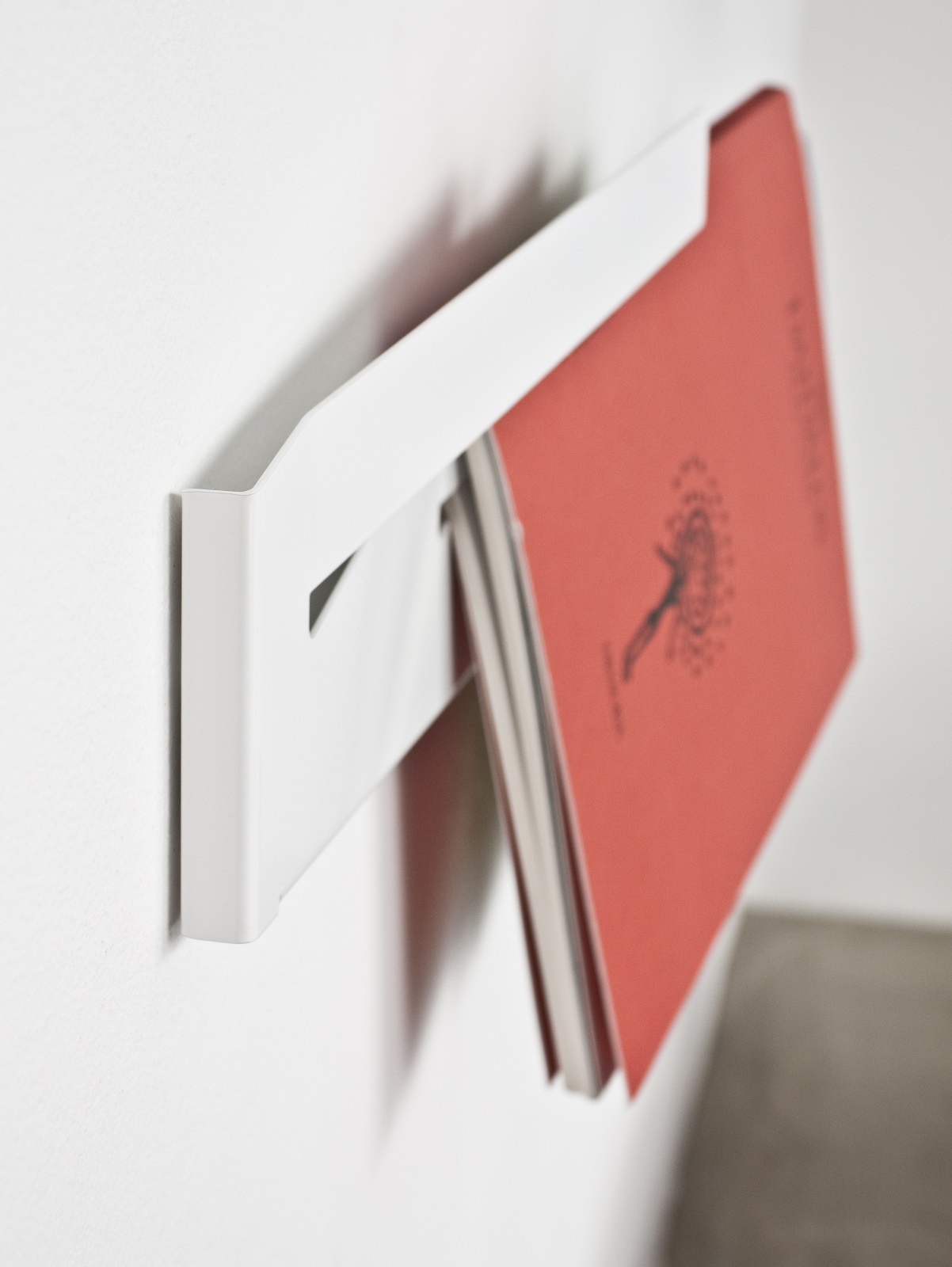 Weißer Müller Möbelwerkstätten Magazinhalter Linea1 an der Wand mit Zeitschriften. Minimalistisches Design.