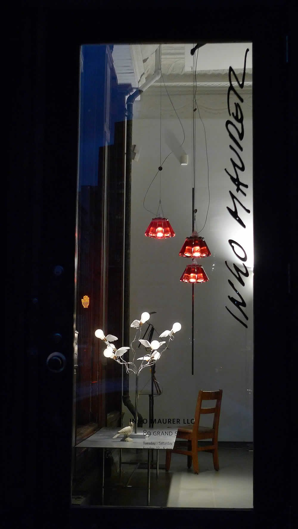 Schaufenster mit Birdies Busch LED Tischleuchte von Ingo Maurer und roten Hängelampen.