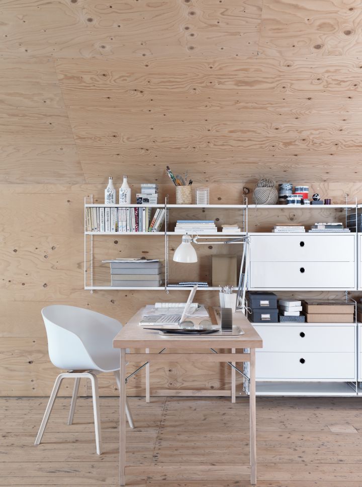 Büro mit String Regalsystem und Schubladenelementen. Walnuss Schreibtisch und weißer Stuhl im modernen Arbeitszimmer.