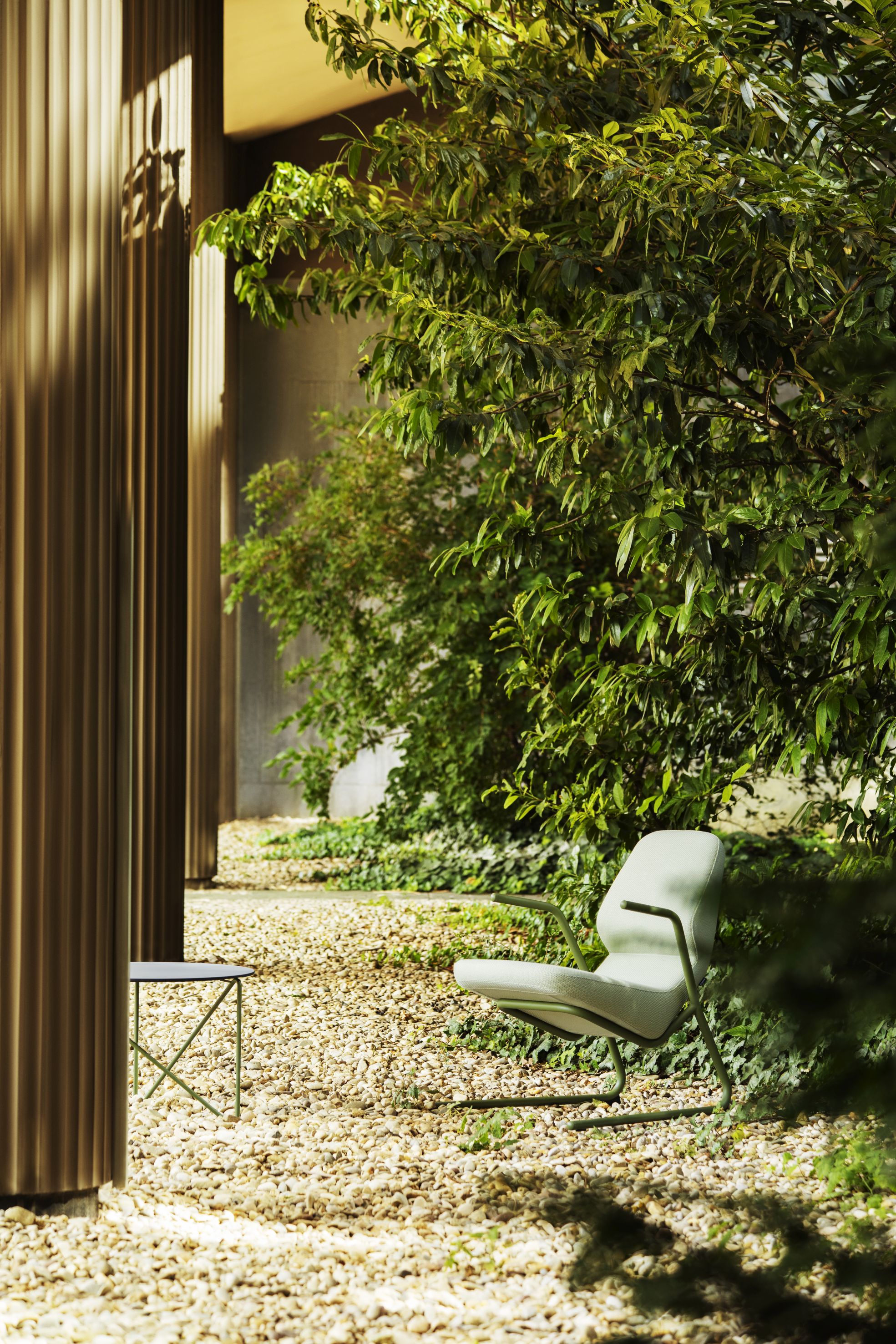 Heller Oblique Sessel von Prostoria für den Innen- und Außenbereich in grüner Umgebung.