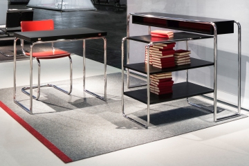B 22 Stahlrohr Regal von Thonet neben passendem Tisch mit rotem Stuhl. Designklassiker.