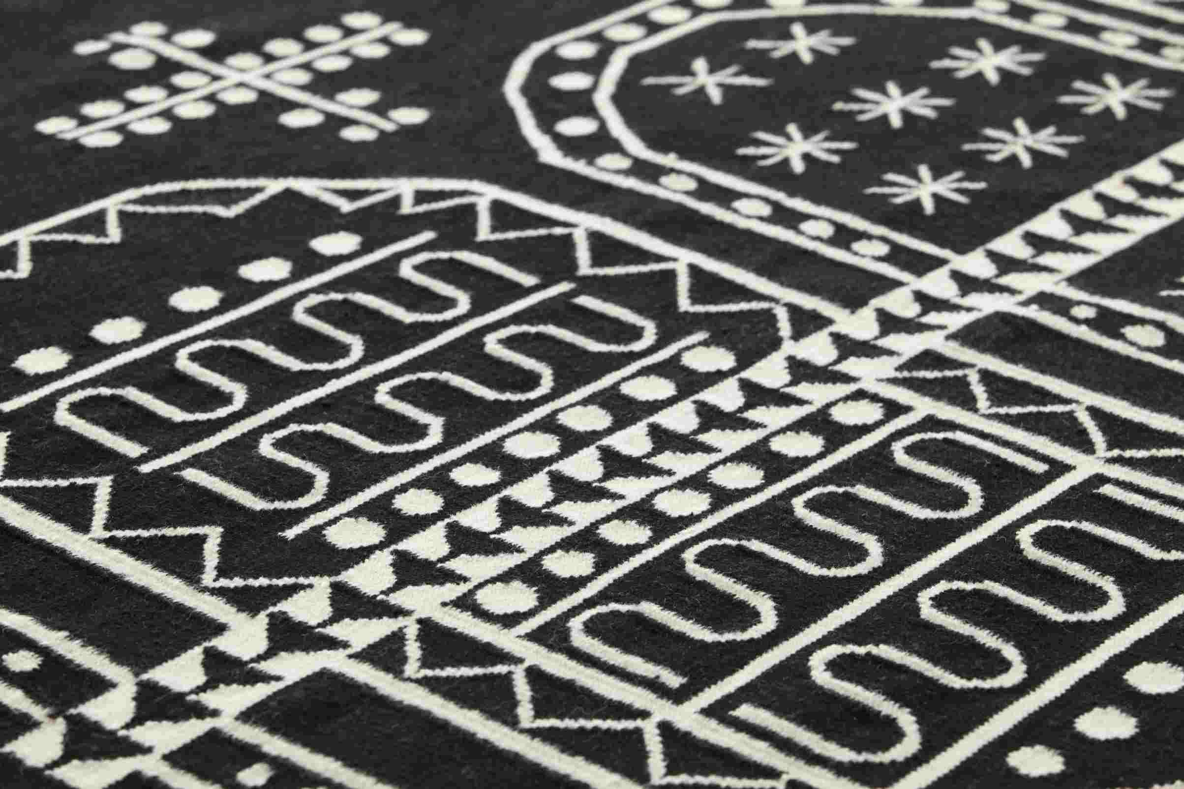 Detailaufnahme des Kilim Teppichs mit geometrischen, weißen Mustern auf schwarzem Grund.