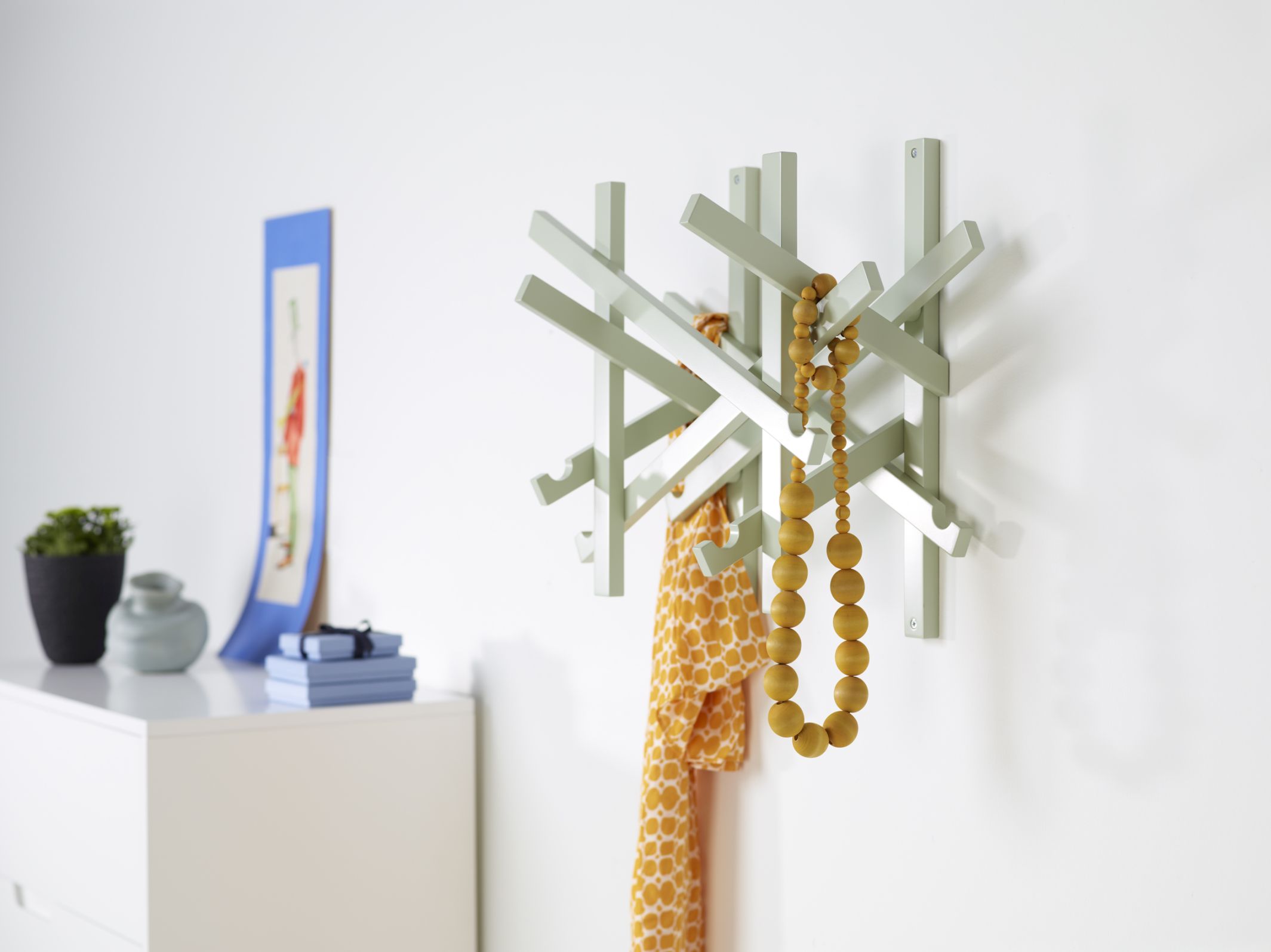 Hellgrüne Wandgarderobe aus Holz mit Schal und Holzkette, moderne Garderobenlösung für Flur und Diele.