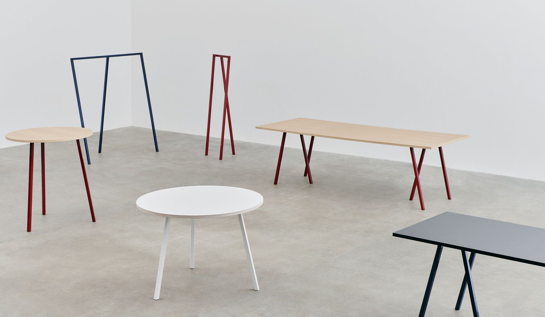 Mehrere Hay Loop Stand Tische in verschiedenen Farben und Formen, minimalistisches Design.