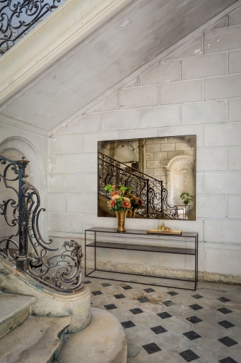 Ethnicraft Wandspiegel "heavy aged bronze" im Interieur mit Konsole, Blumen und Treppenhaus-Reflexion für stilvolle Dekoration.