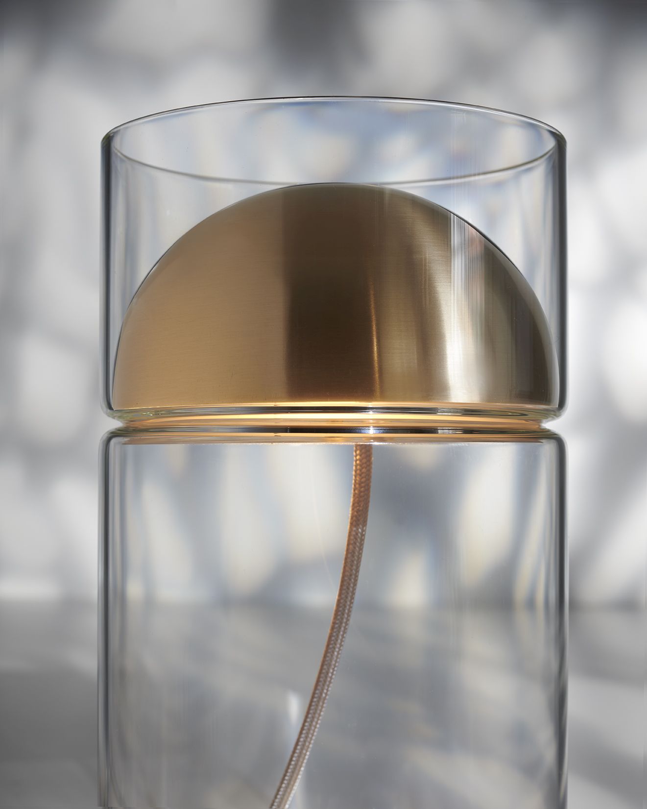 Oluce Medusa Tischleuchte: Moderne Lampe mit goldenem Schirm und transparentem Glaszylinder.