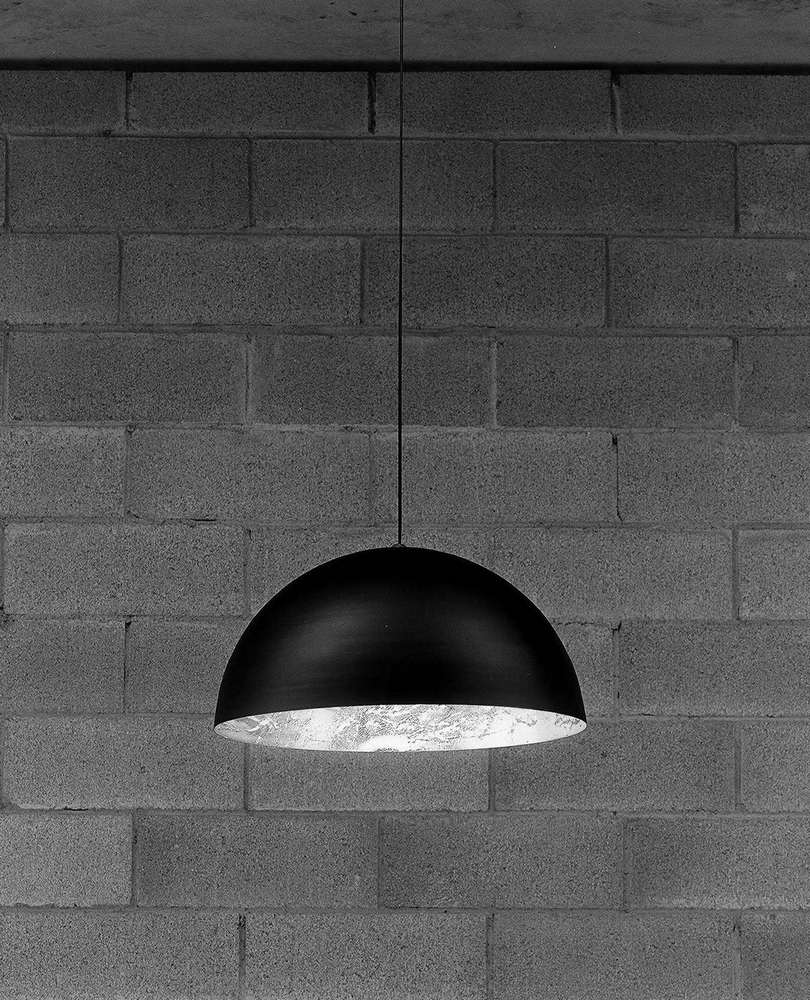 Schwarze Stchu-Moon Hängeleuchte von Catellani & Smith mit silberfarbener Innenseite vor einer grauen Ziegelwand.