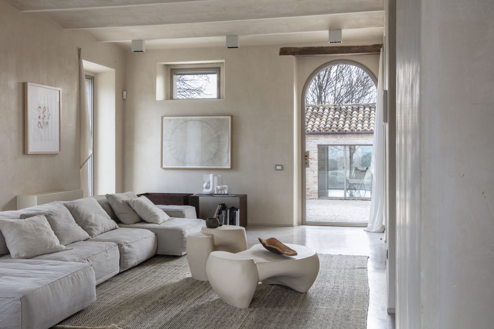 Helles Wohnzimmer mit modularem Sofa, Design Couchtisch und Blick in den Garten. Moderne Inneneinrichtung.