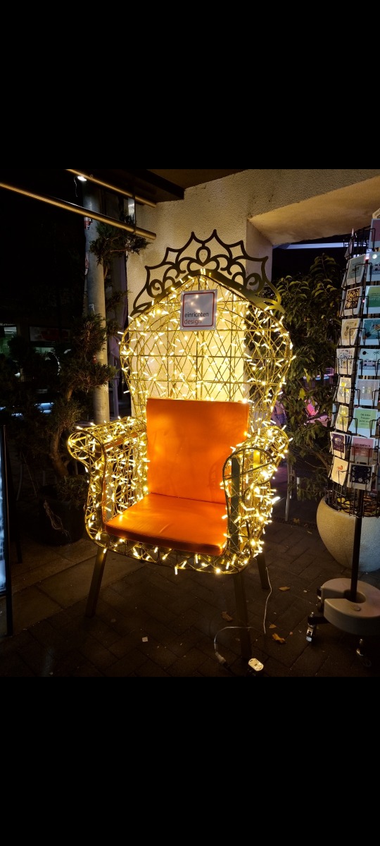 Leuchtender Sessel mit orangenem Kissen und Lichterketten, ein Einzelstück für besondere Momente.
