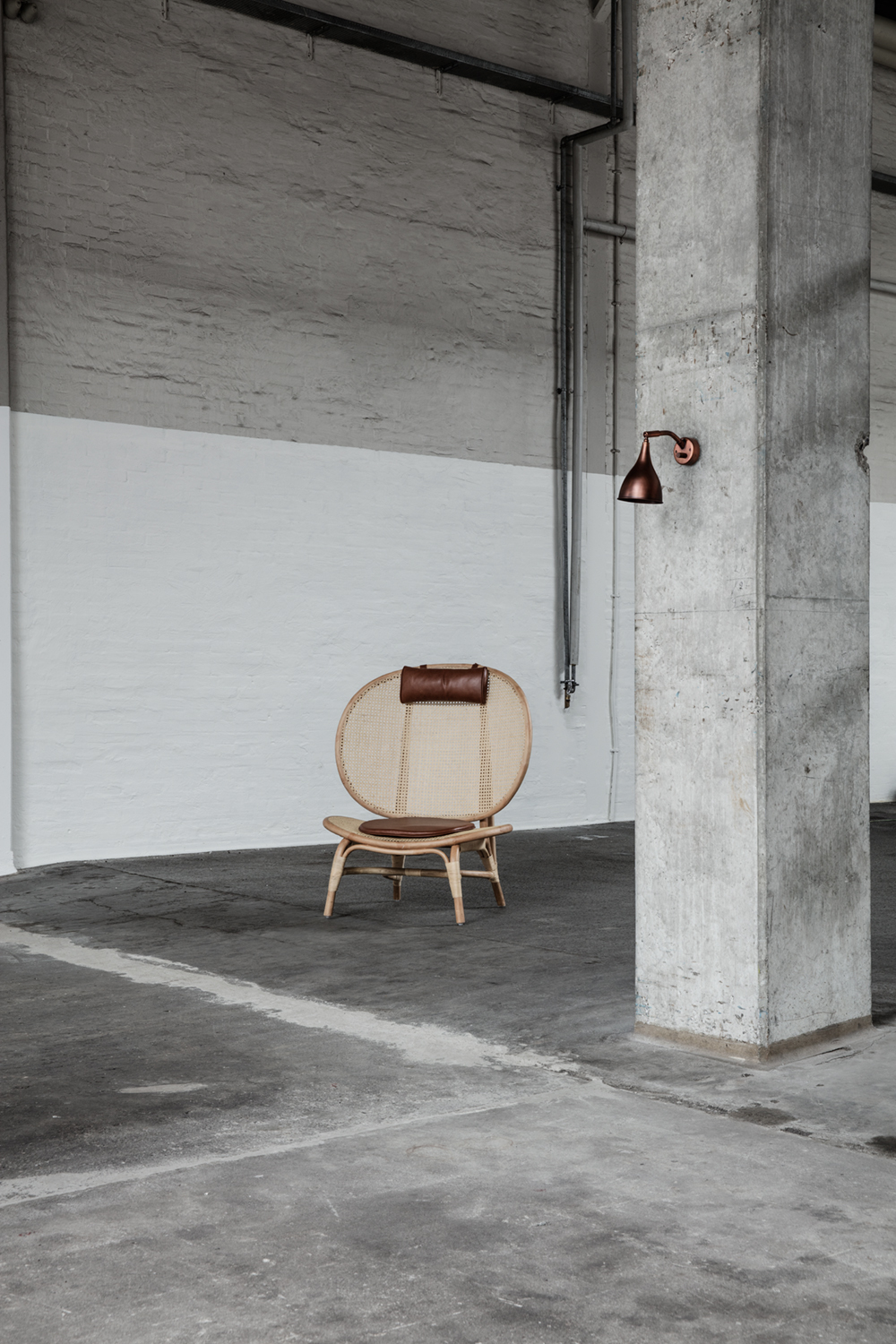 Nomad Chair Cognac von NORR11: Rattan Sessel mit Lederkissen in modernem Industrieraum.