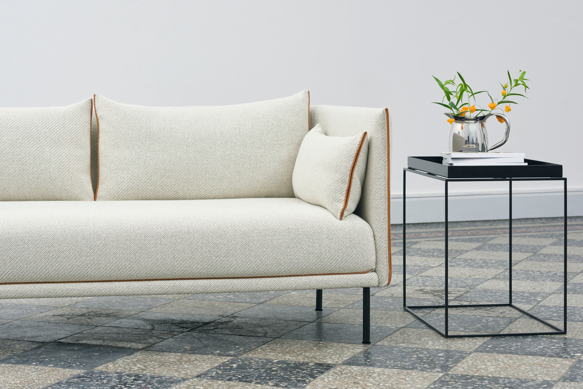 Hay Tray Table S Beistelltisch aus schwarzem Metall neben einem modernen Sofa mit Zierleiste.