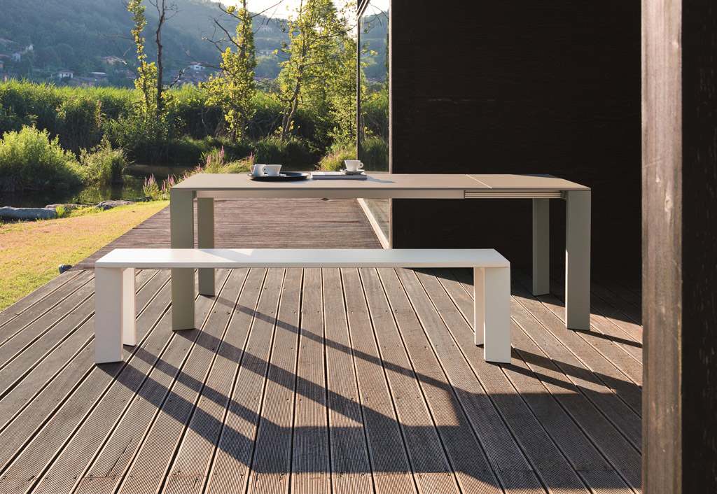 Weiße Grande Arche Outdoor Bank aus Metall vor passendem Esstisch auf Holzterrasse.