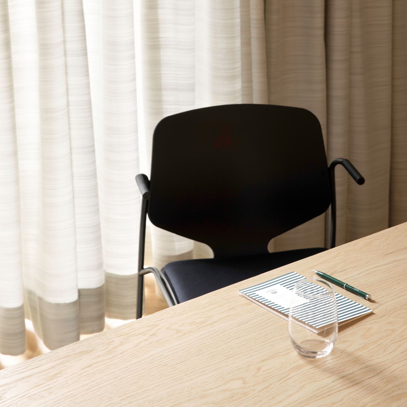 Schwarzer Nova Sea Stuhl mit Armlehne und Polsterung am Tisch, modernes Möbeldesign.