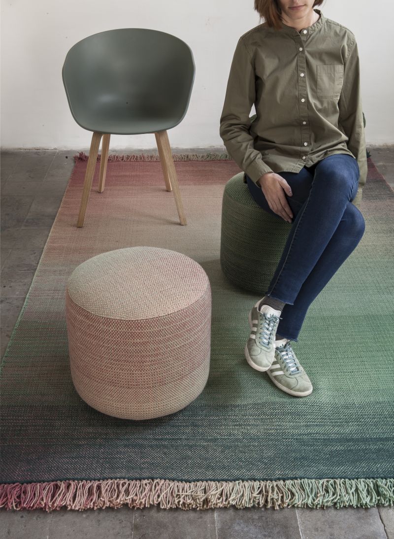 Nanimarquina Shade Pouf Hocker 2B: Frau sitzt auf grünem Pouf, daneben rosa Hocker.