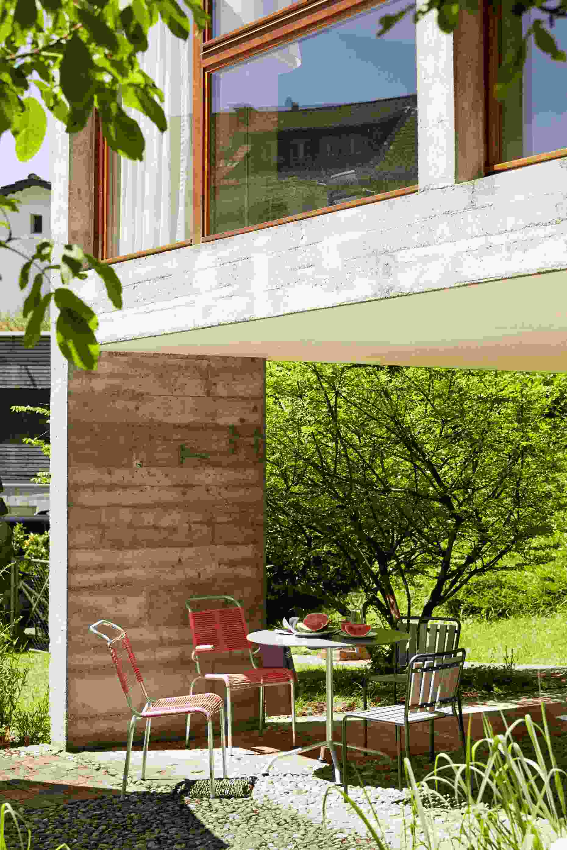 Altorfer Sessel Outdoor Embru Graphitschwarz auf Terrasse mit Gartentisch und Wassermelone. Design Gartenmöbel.