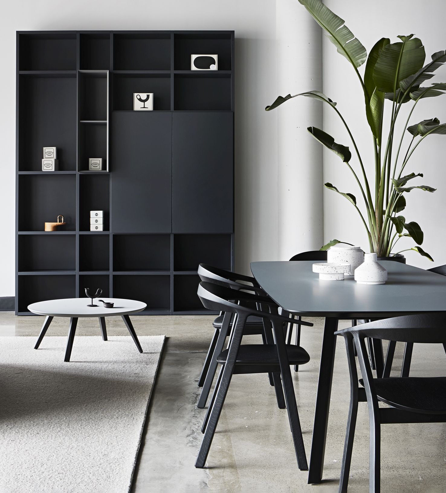 Esszimmer mit Prostoria Rhomb Tisch, schwarzen Stühlen, Regal und Zimmerpflanze. Modernes Möbeldesign.