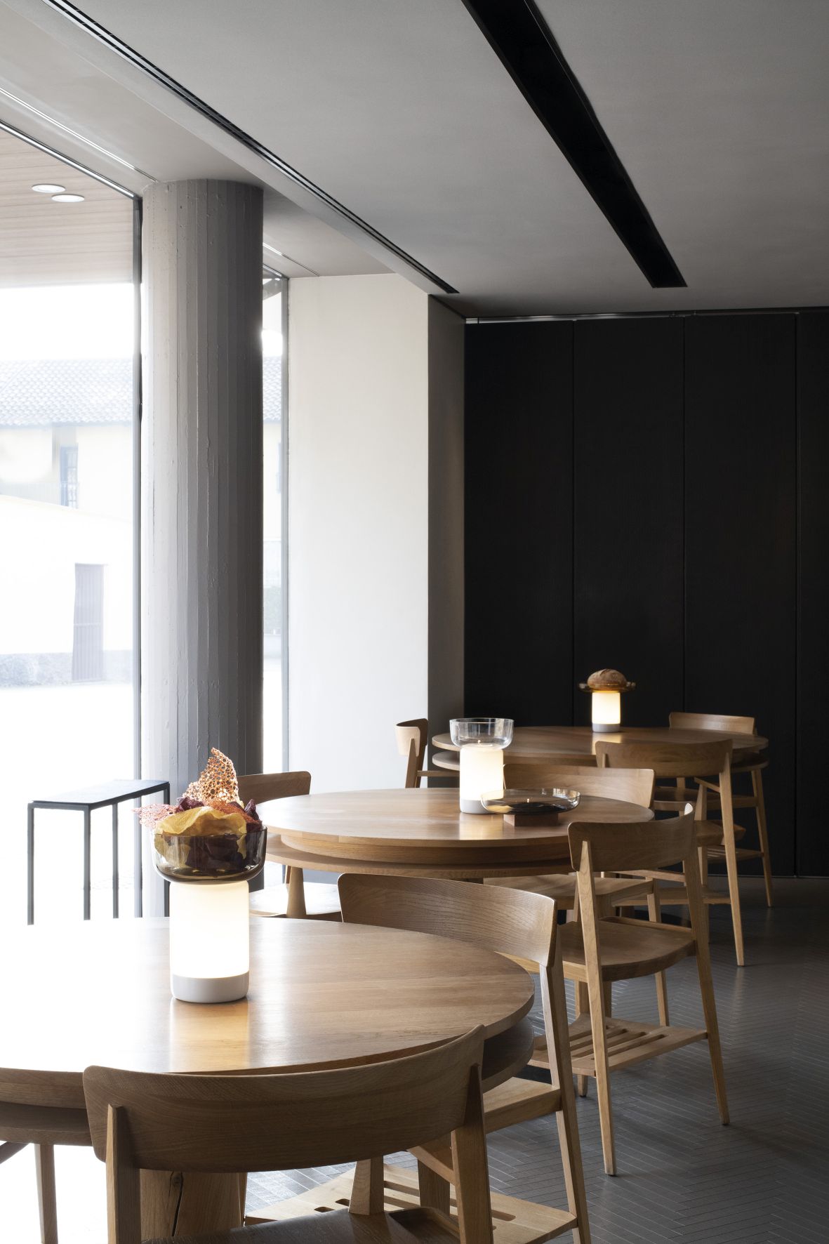 Bontà Akkuleuchte von Artemide auf Holztisch in einem Restaurant, warmes Licht.