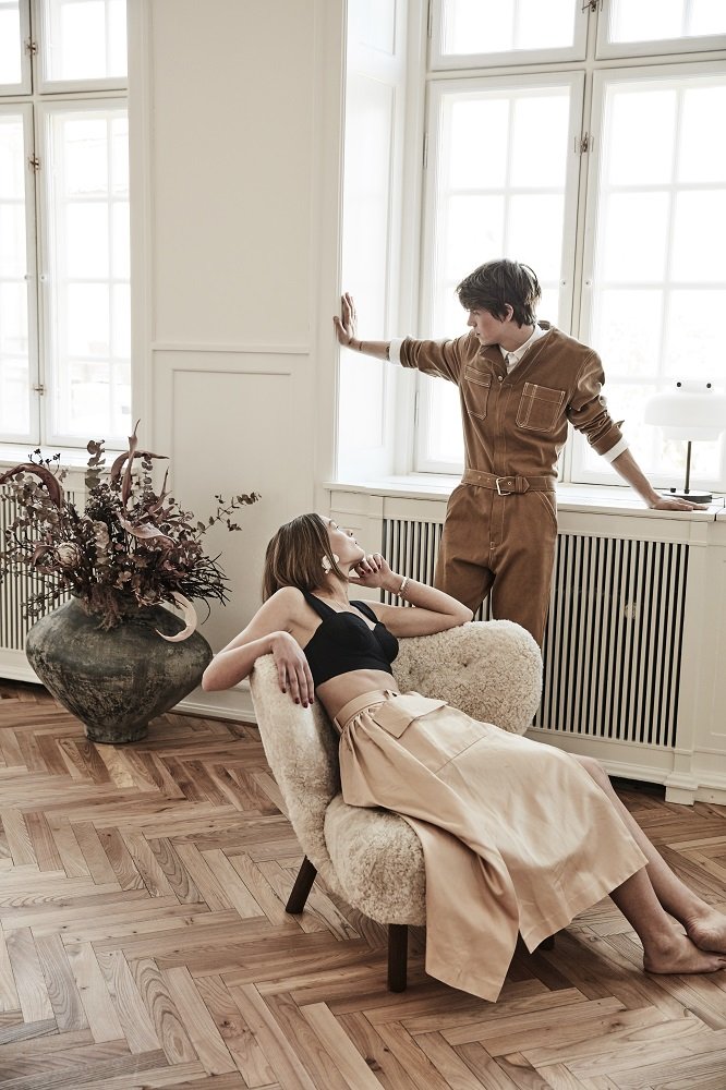 Frau entspannt im Little Petra Sessel von &Tradition, Walnuss-Gestell, Moonlight-Bezug. Gemütlicher Lounge Sessel.