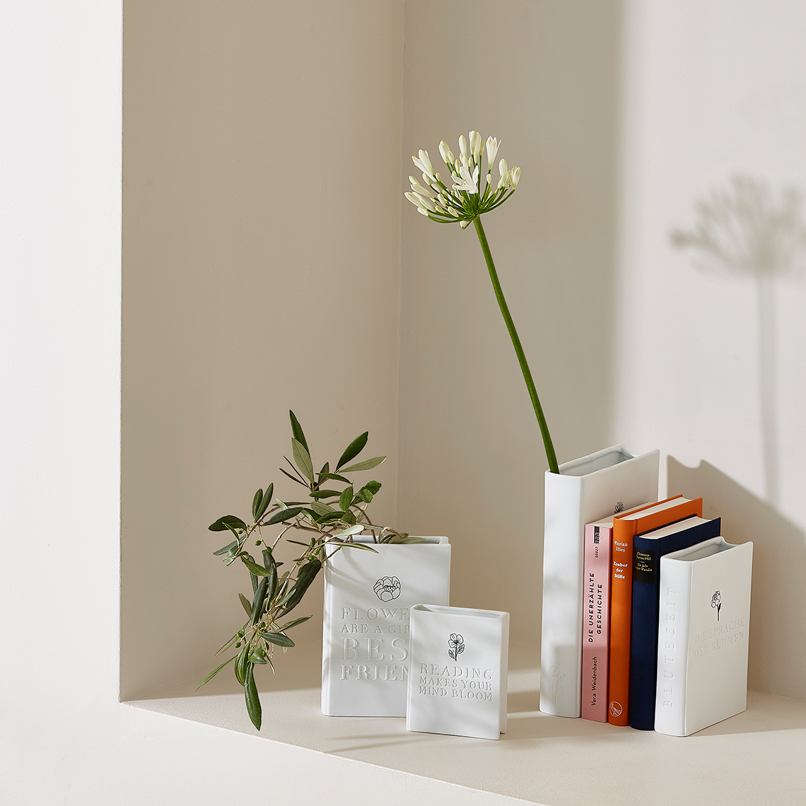 Weiße Räder Blütenzeit Vase mit Blumen und Büchern, moderne Dekoration für Wohnambiente.