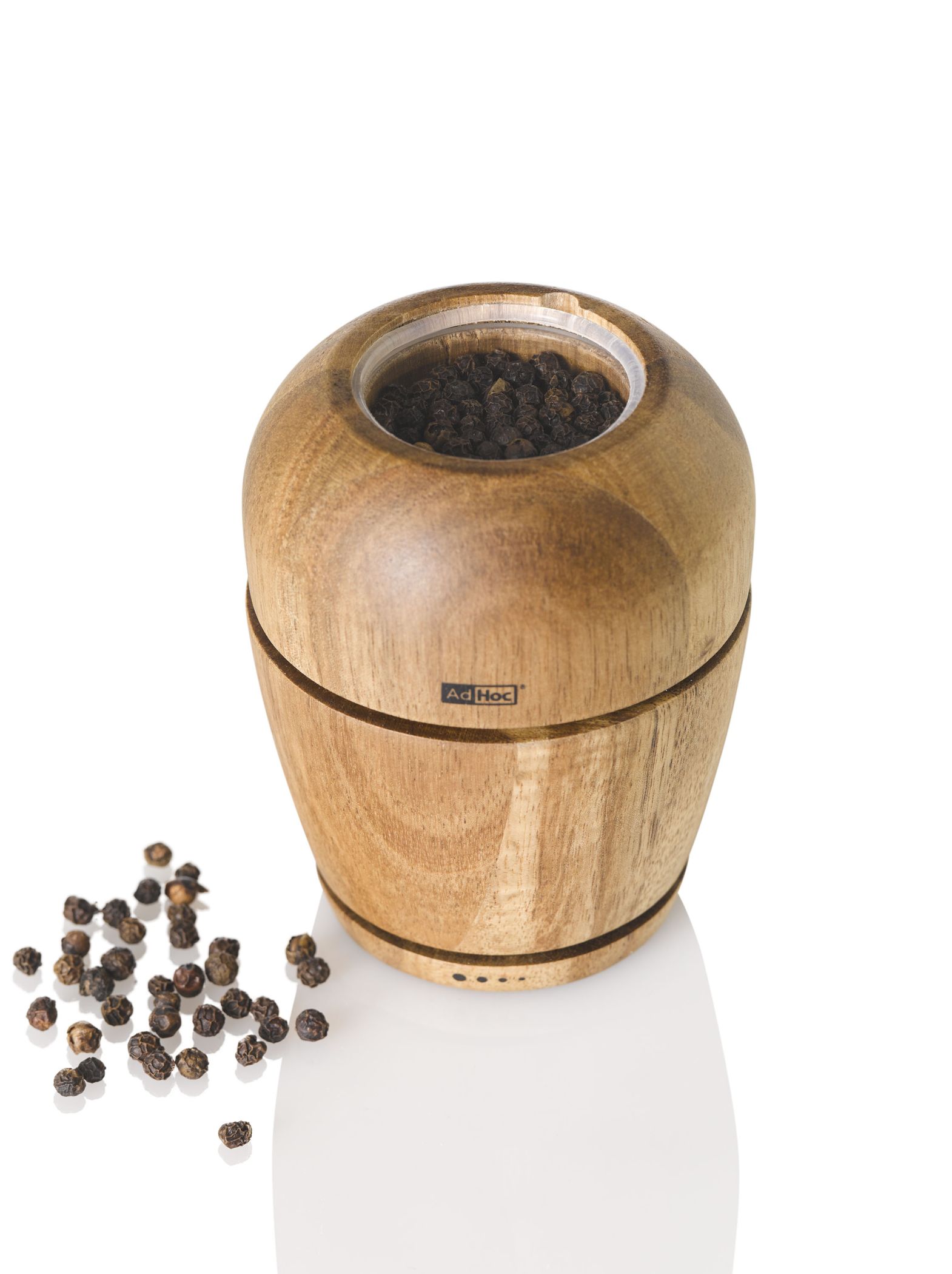 AdHoc Wish Pfeffermühle aus Akazienholz, gefüllt mit schwarzen Pfefferkörnern, auf weißem Hintergrund.