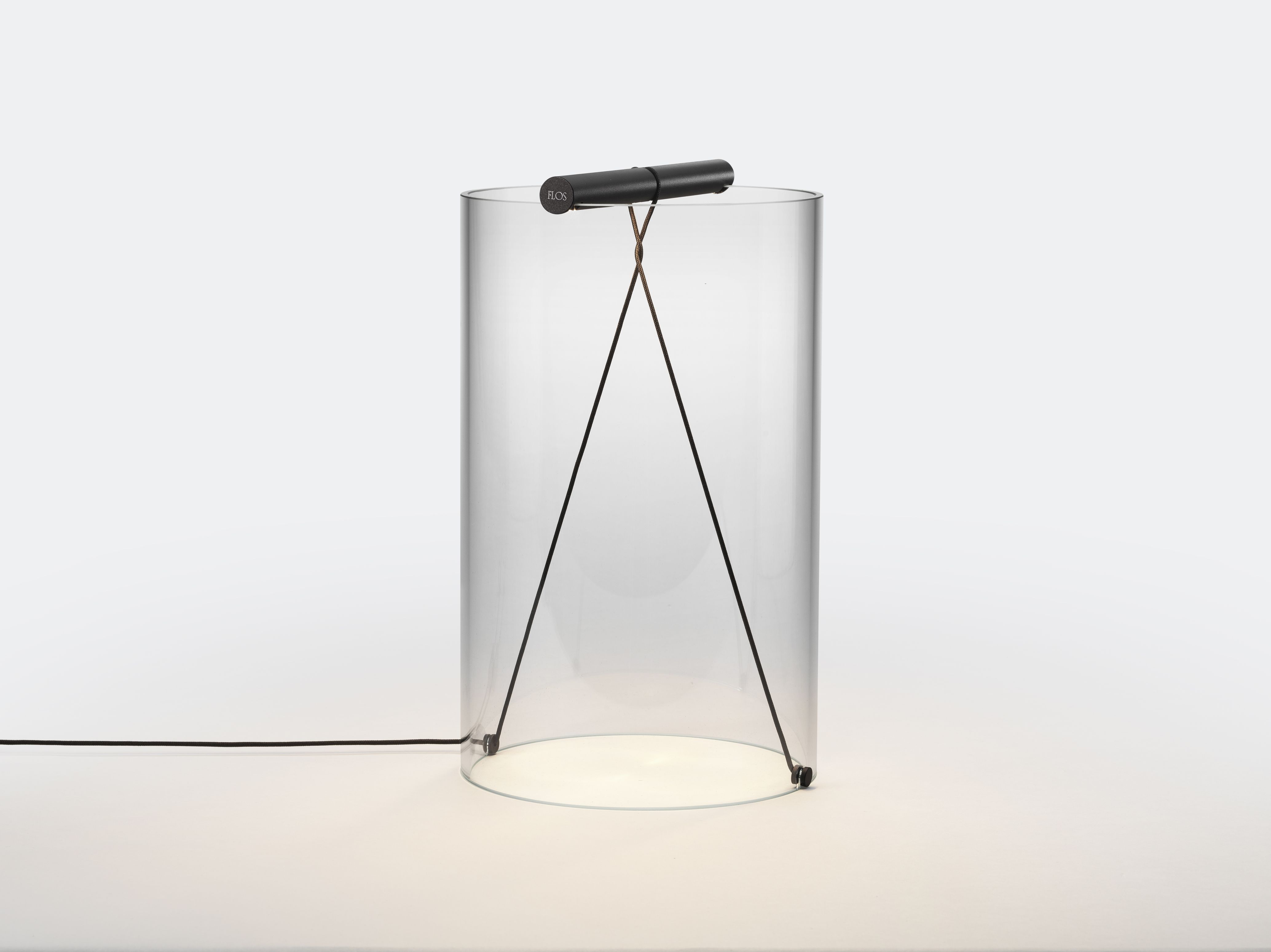 To-Tie T2 LED Tischleuchte von Flos, schwarzer Stab über transparentem Zylinder mit Kabeln.
