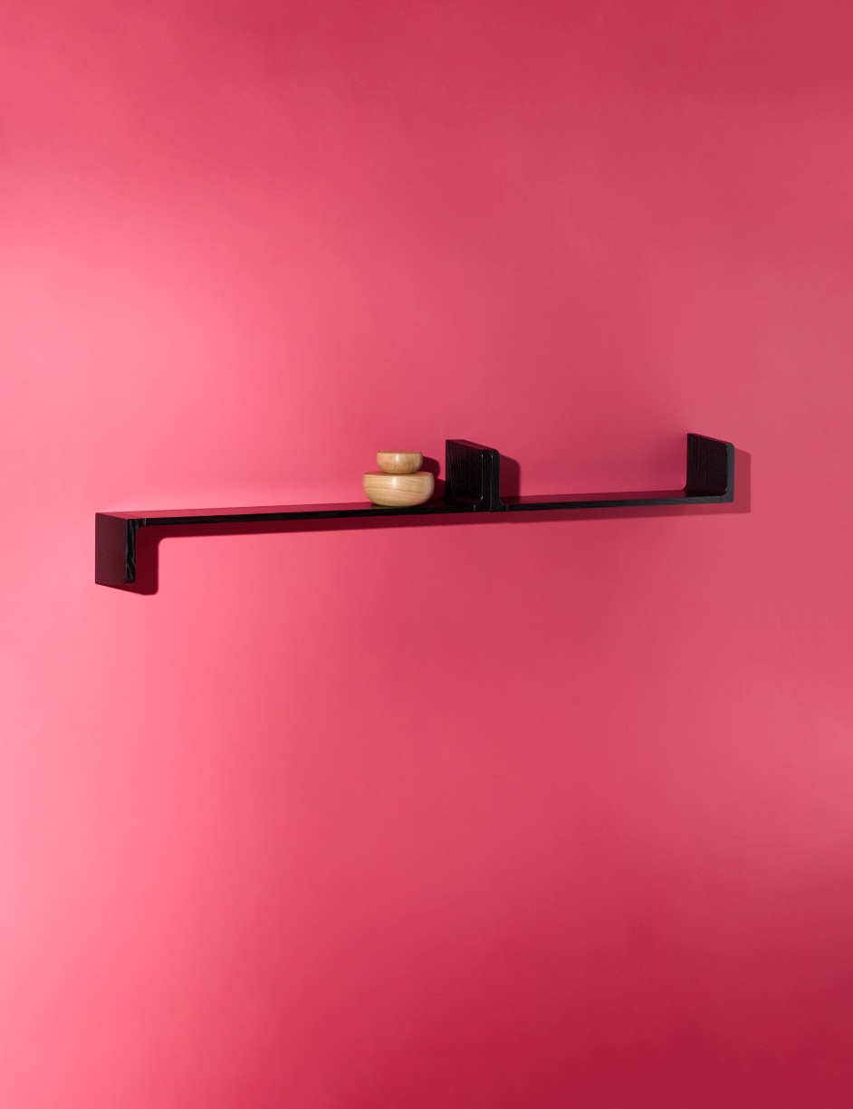 Schwarzes Ulna Wandregal von Schönbuch an pinker Wand mit zwei kleinen Holzschalen dekoriert.