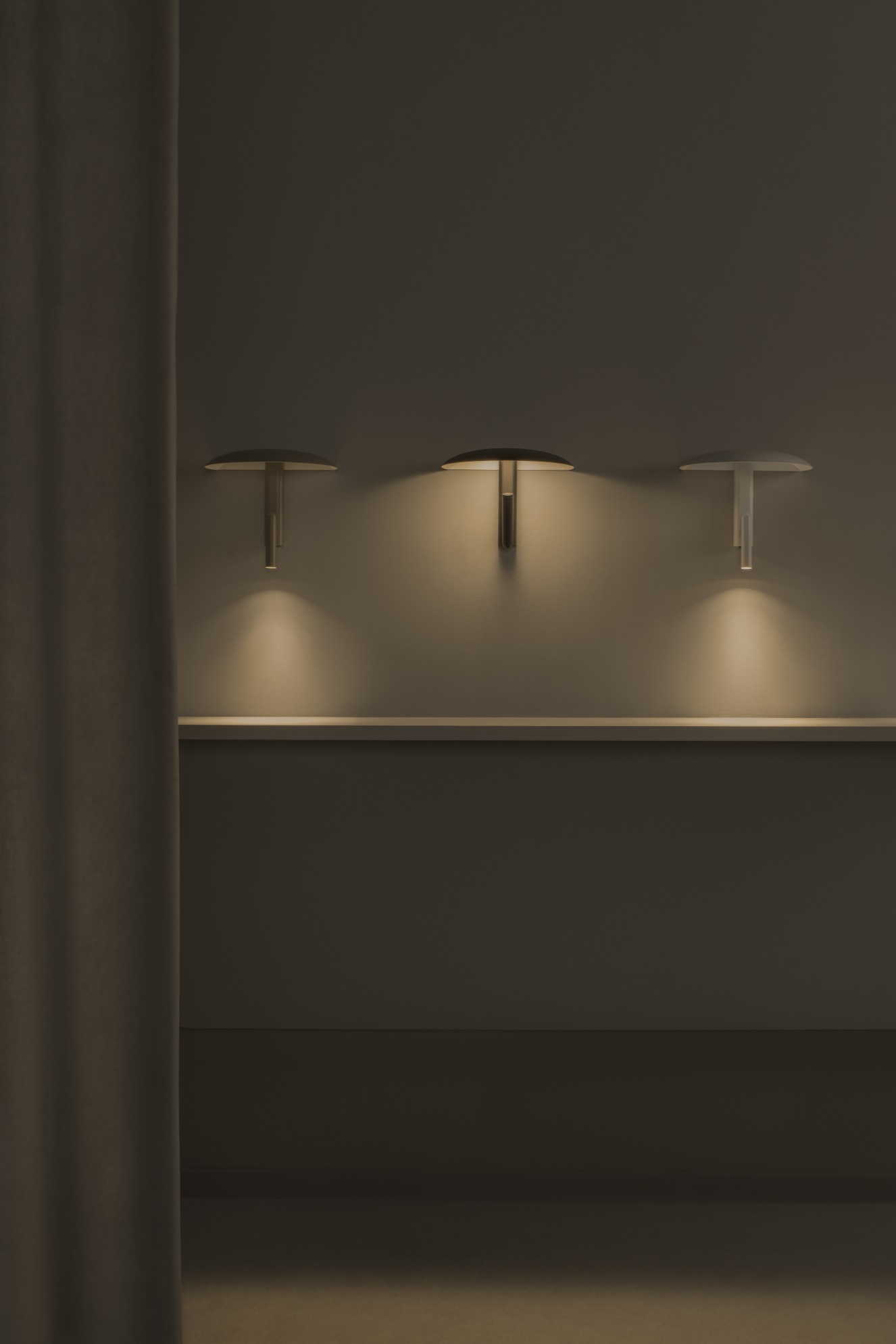 Drei Konoha Wandleuchten von Marset in verschiedenen Farben an einer Wand mit Vorhang.