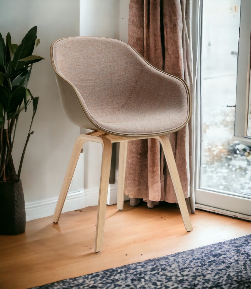 About A Chair AAC222 Stuhl mit Eichengestell und beigem Stoffbezug vor Fenster.