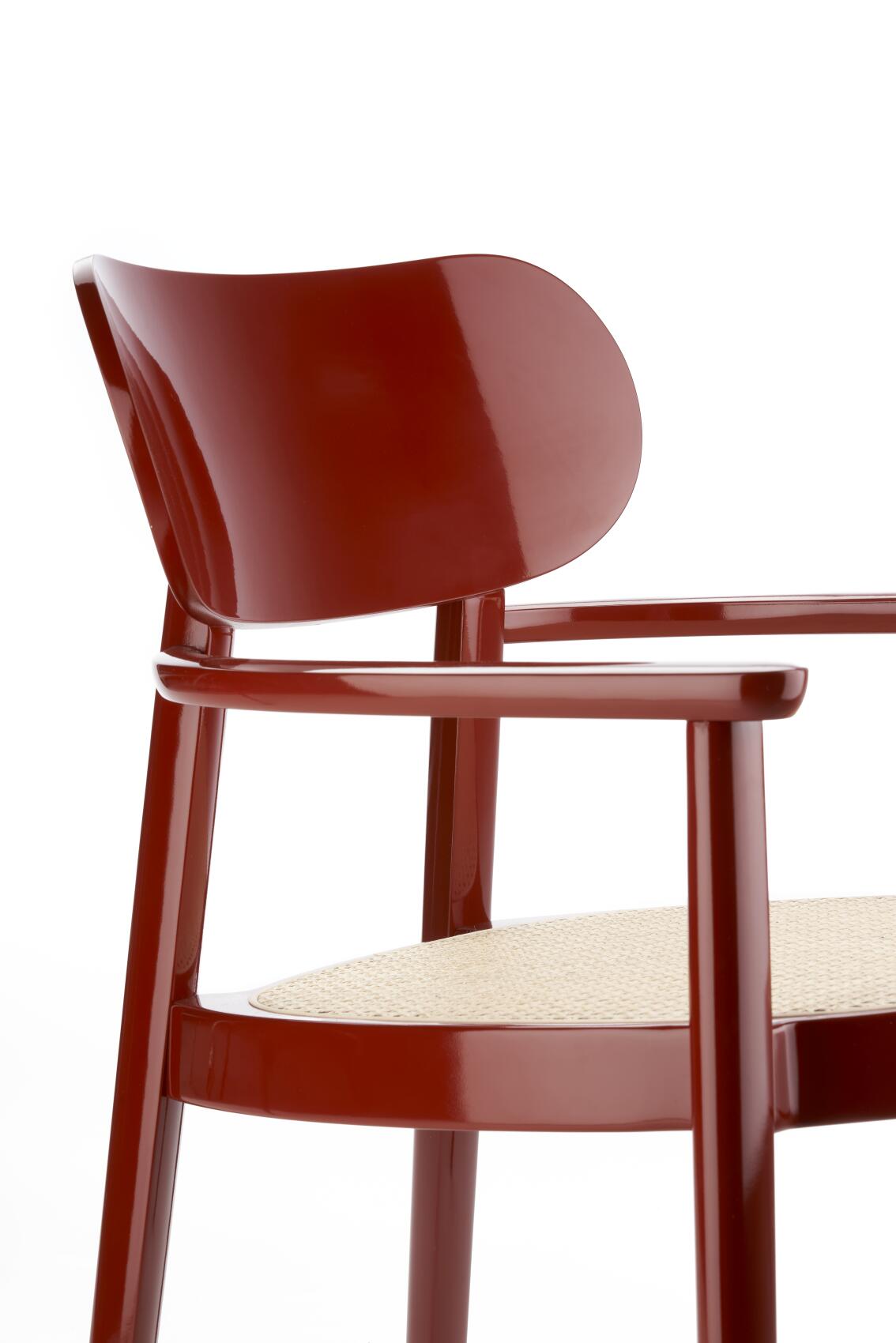 Detailaufnahme: Roter Holzsesessel mit Armlehnen und Wiener Geflecht Sitzfläche, Thonet Stil.