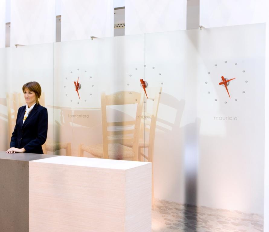 Rodón Mini Wanduhren von Nomon mit roten Zeigern an einer Rezeption.