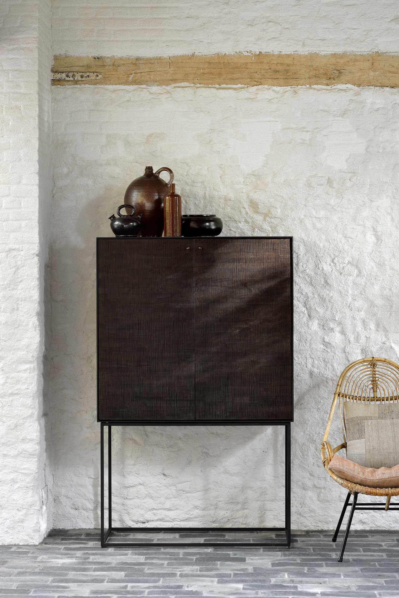 Ethnicraft Teak Grooves Schrank: Moderner Holzschrank mit gerillten Türen und minimalistischem Metallgestell vor weißer Wand.