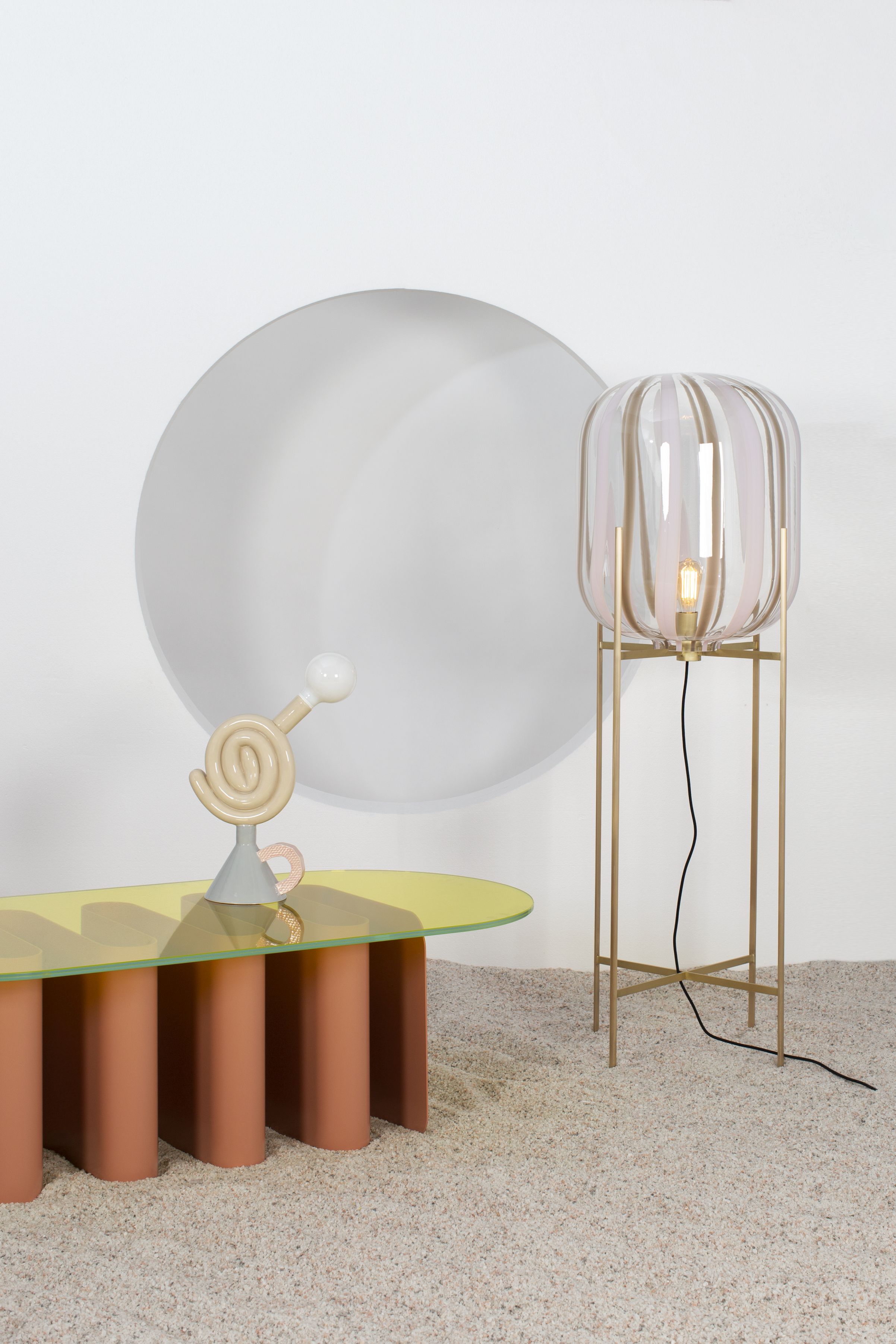 Tavolo2 Esstisch von Pulpo mit gelber Glasplatte und rosa Säulen, dazu eine Stehlampe.