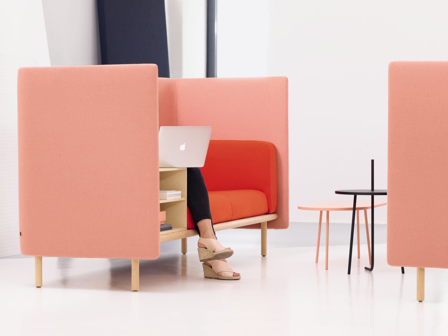 Floater Sofa von Cor: Frau arbeitet am Laptop im modernen, orangefarbenen 2-Sitzer Sofa.