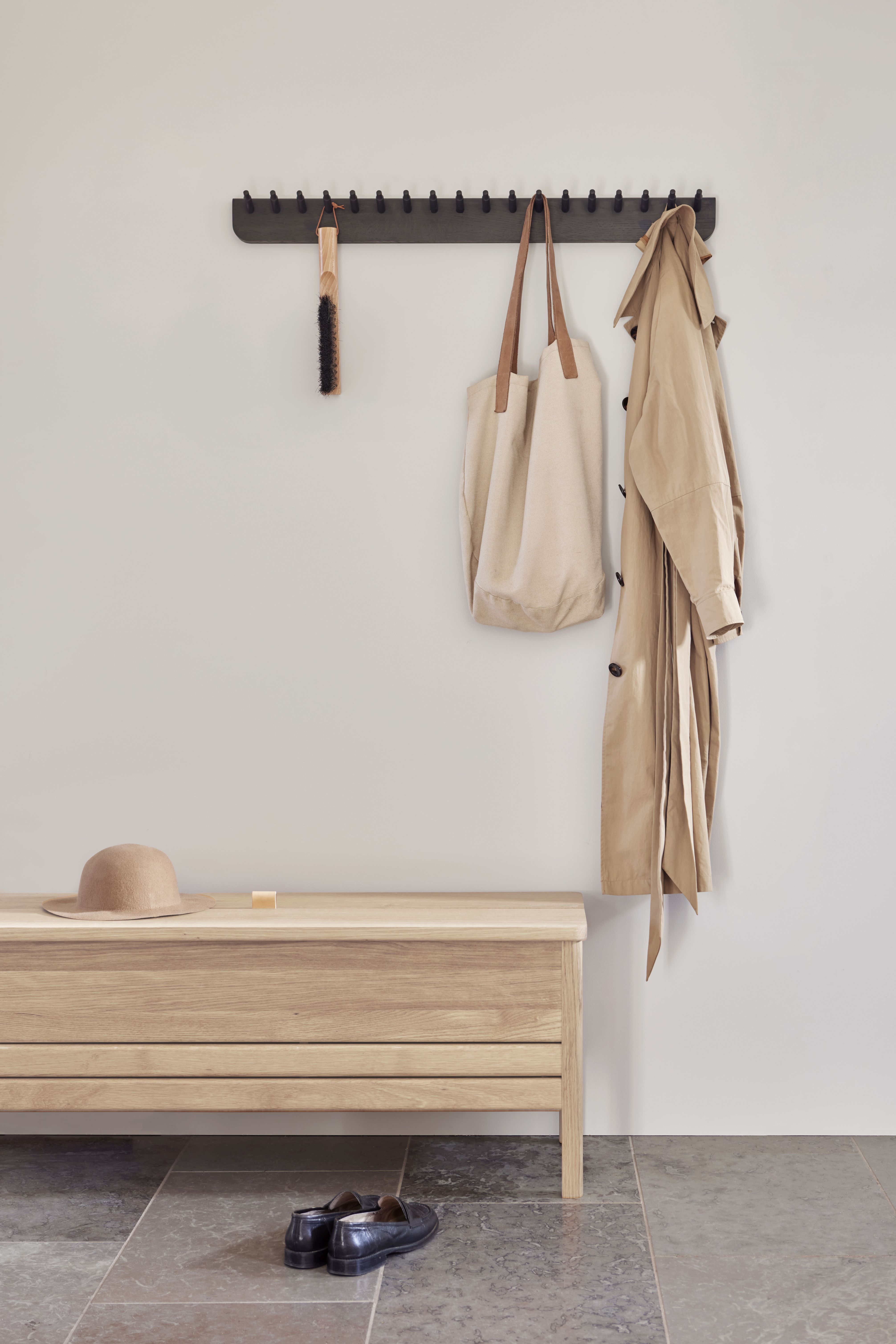 Echo Garderobenleiste Eiche von Form & Refine mit Kleidung, Tasche und Bank.