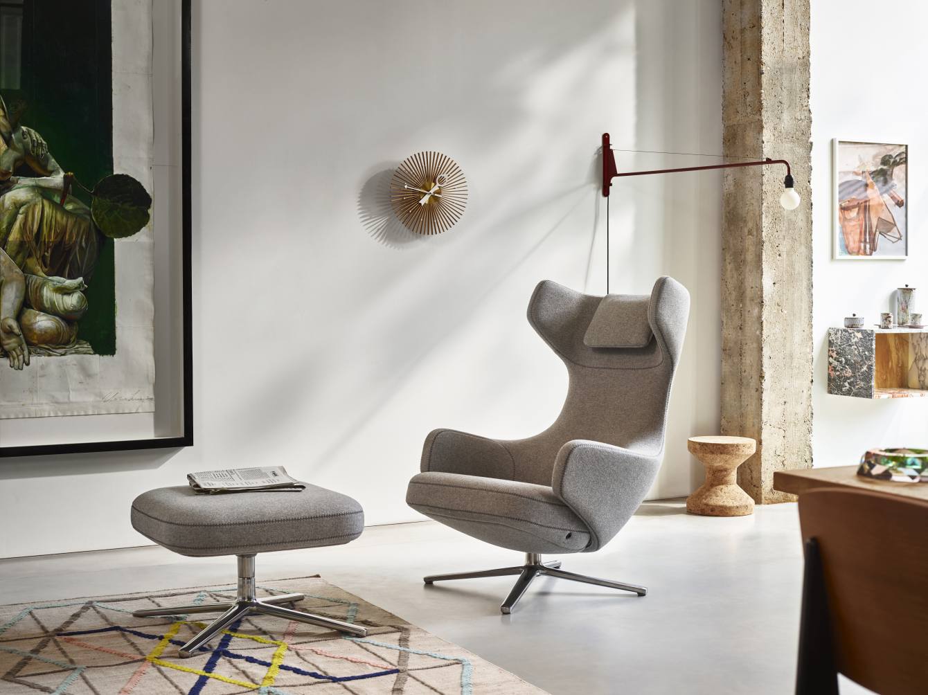 Wohnzimmer-Szene mit Vitra Sessel, Hocker und der goldenen Popsicle Clock Wanduhr.