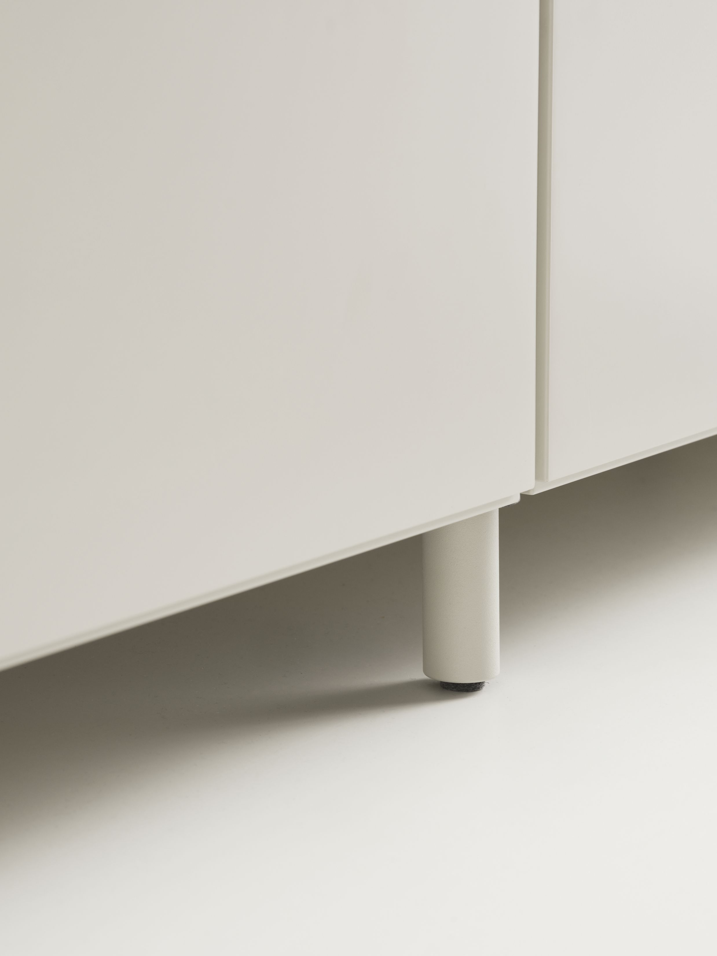 Detailaufnahme: Graue Kommode mit Relief Beine von String Furniture. Möbeldesign für Wohnzimmer.