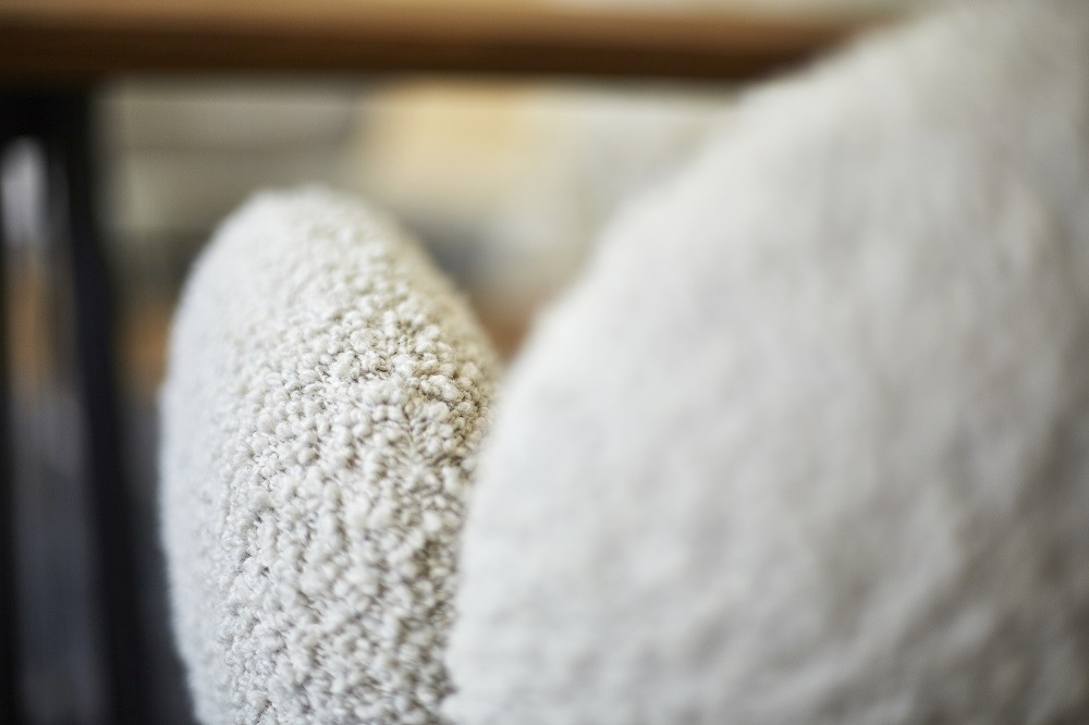 Detailaufnahme: Nana Armchair Armlehnenstuhl von Freifrau Manufaktur mit flauschigem, hellem Stoffbezug. Gemütlicher Sessel für Wohnzimmer.