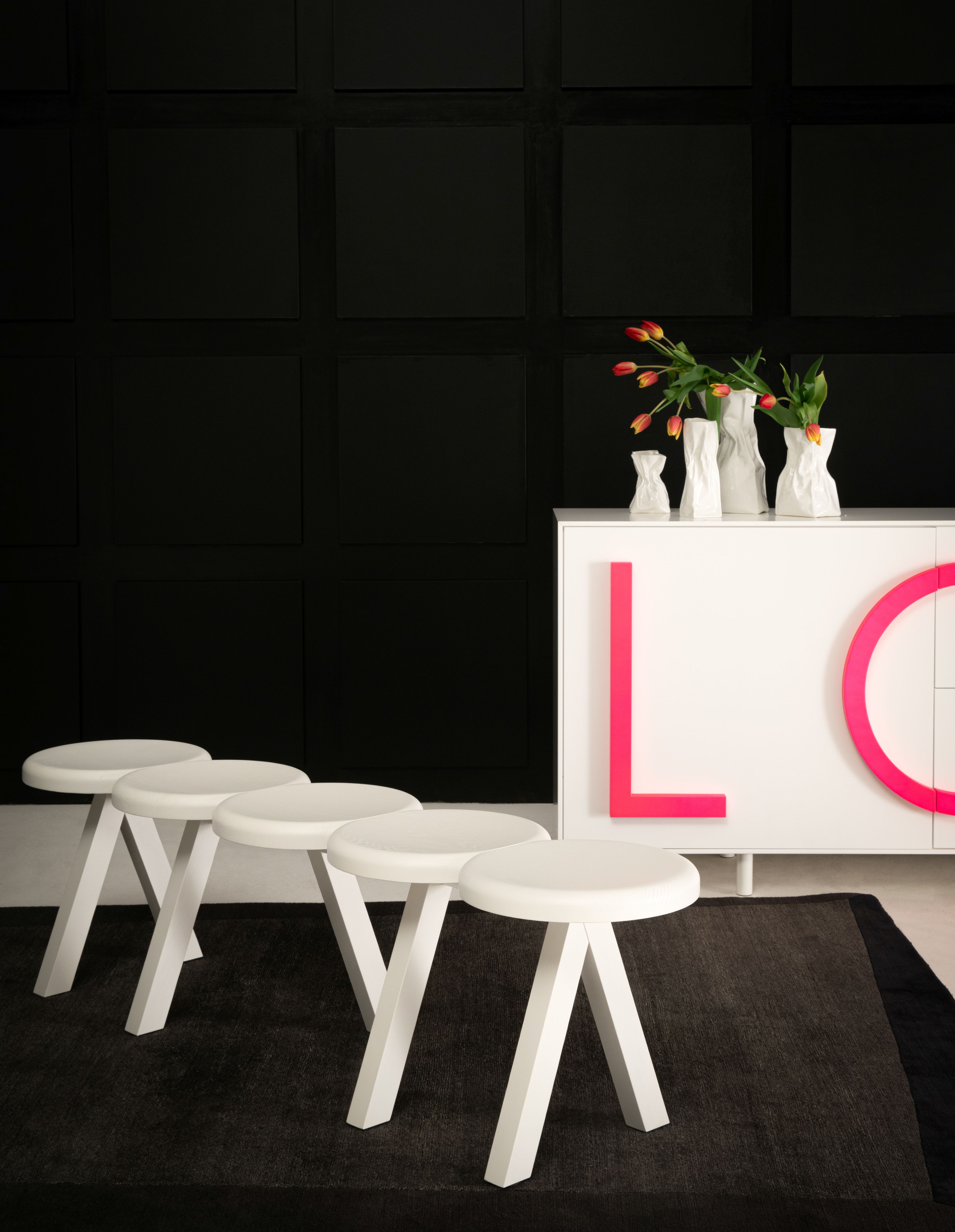 Weiße Millepiedi Bank von Driade vor schwarzer Wand und modernem Sideboard. Design Möbel.