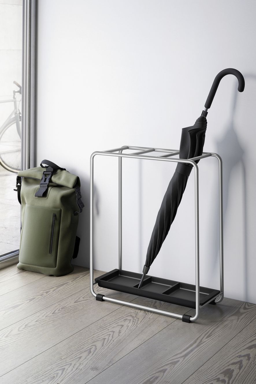 Moderner Mecor Schirmständer ZACK mit schwarzem Schirm und Rucksack im Flur. Metall Schirmhalter.