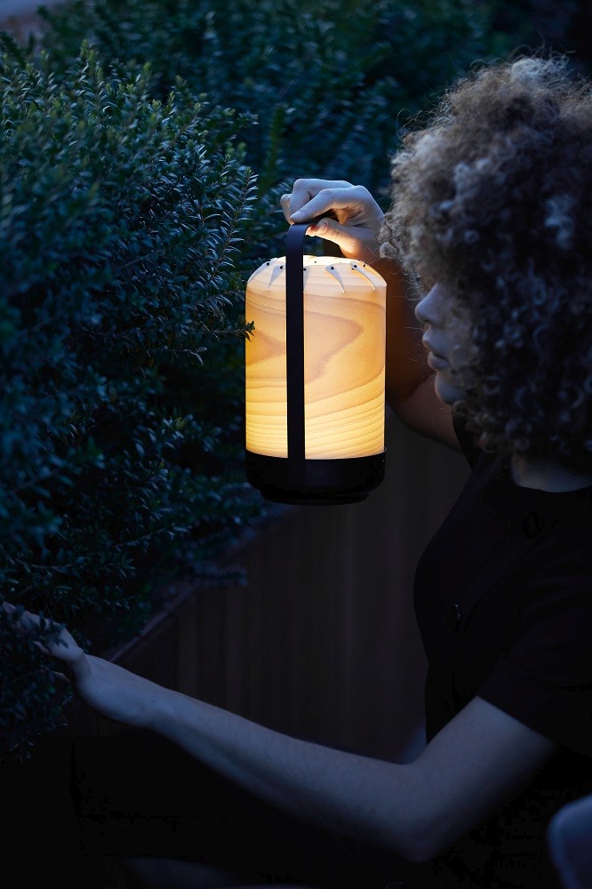 Frau hält Chou Mini LED Akkuleuchte von LZF Lamps im Garten. Tischleuchte mit USB.