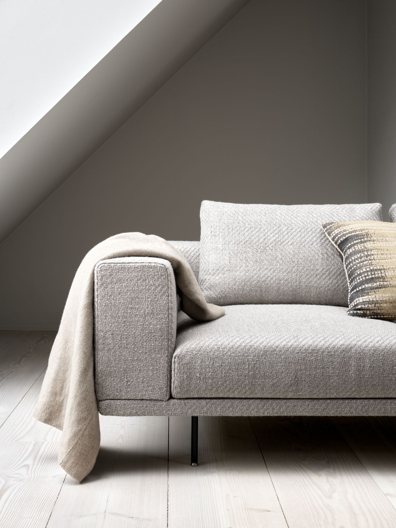 Detailaufnahme des grauen Loft Modul Sofas (3-Sitzer) von Vipp mit Kissen und Decke. Modernes Design Sofa.